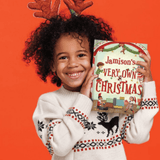 A child holding their own personalised christmas book with their name on the front cover.