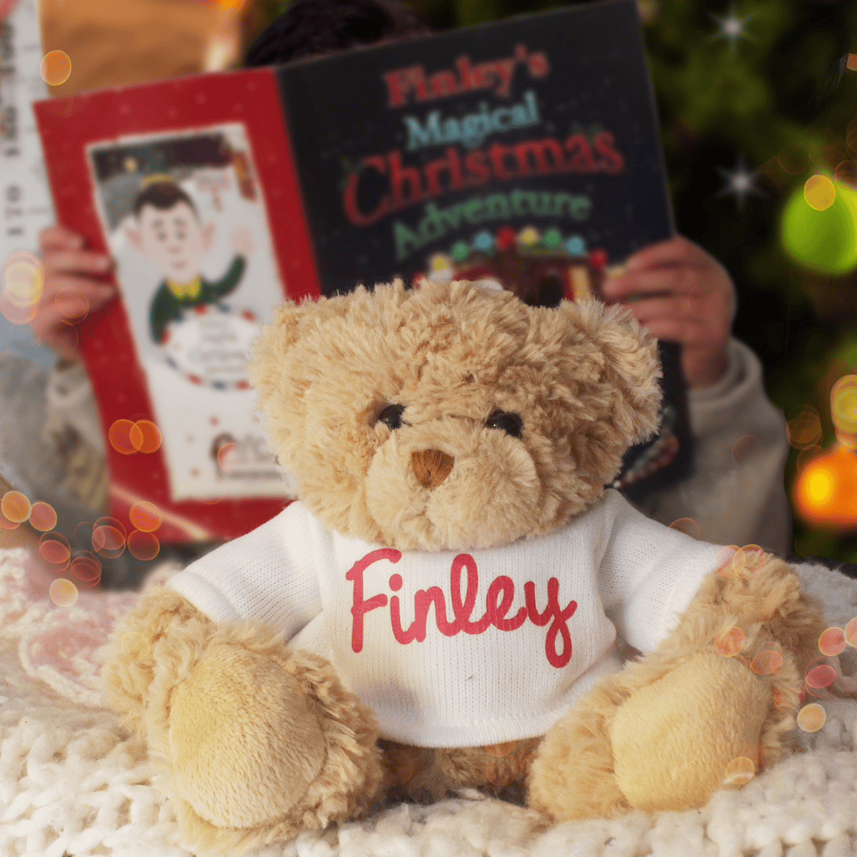 personalised teddy bear wearing a jumper with the child's name on the front and a personalised christmas story book behind