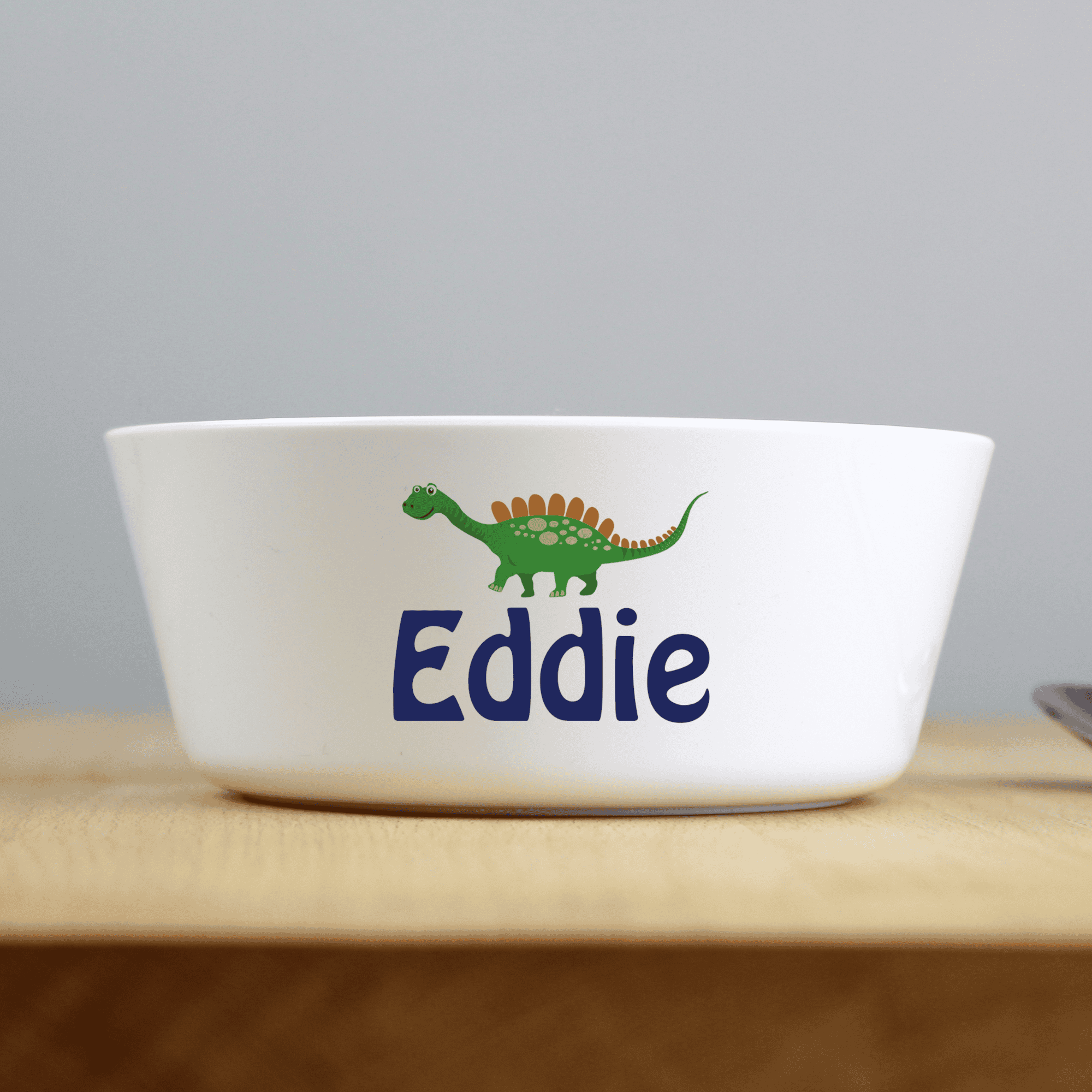 personalised dinosaur plastic bowl with any name personalised on the side of the bowl below a dinosaur image