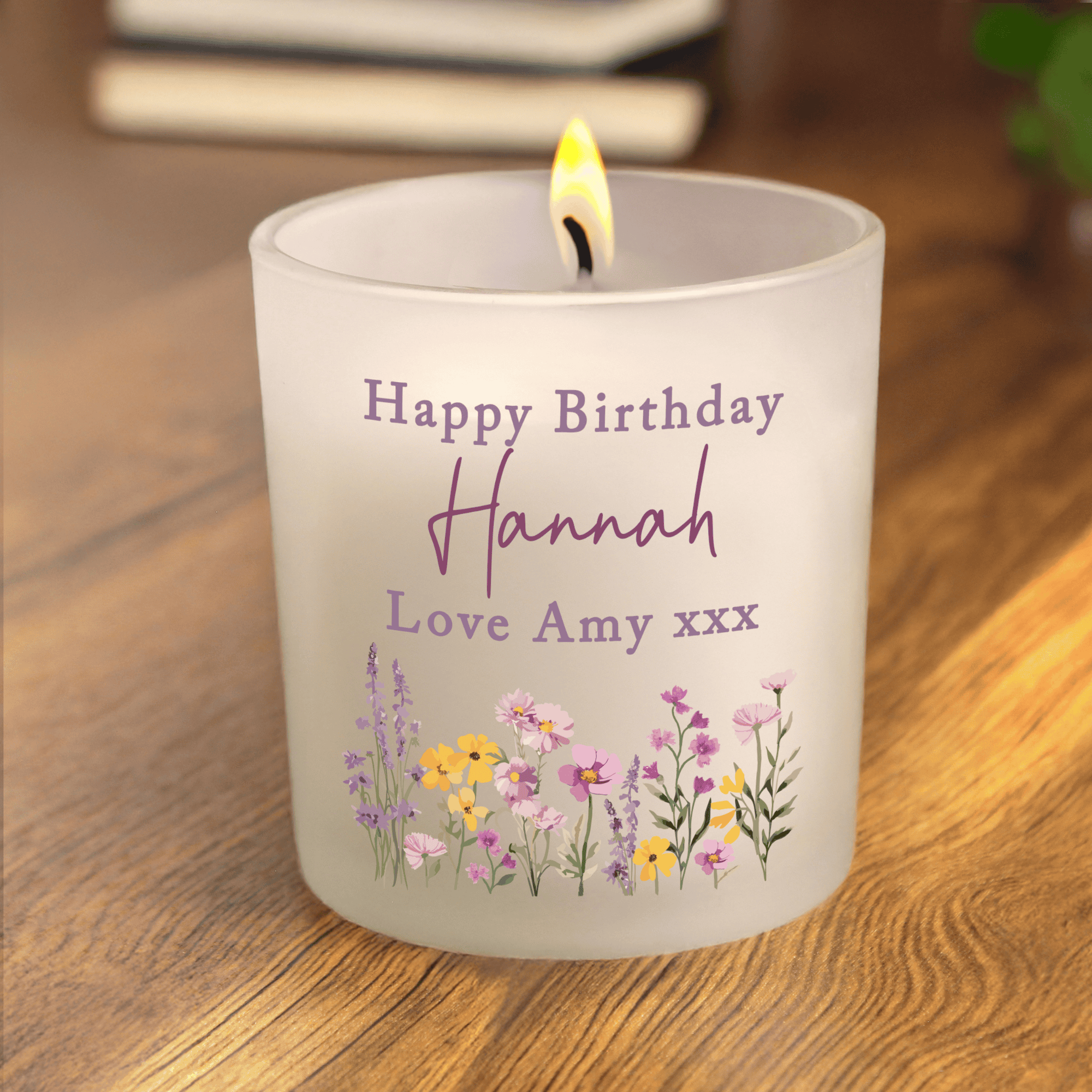 Personalized birthday candle with floral design and text on a wooden surface