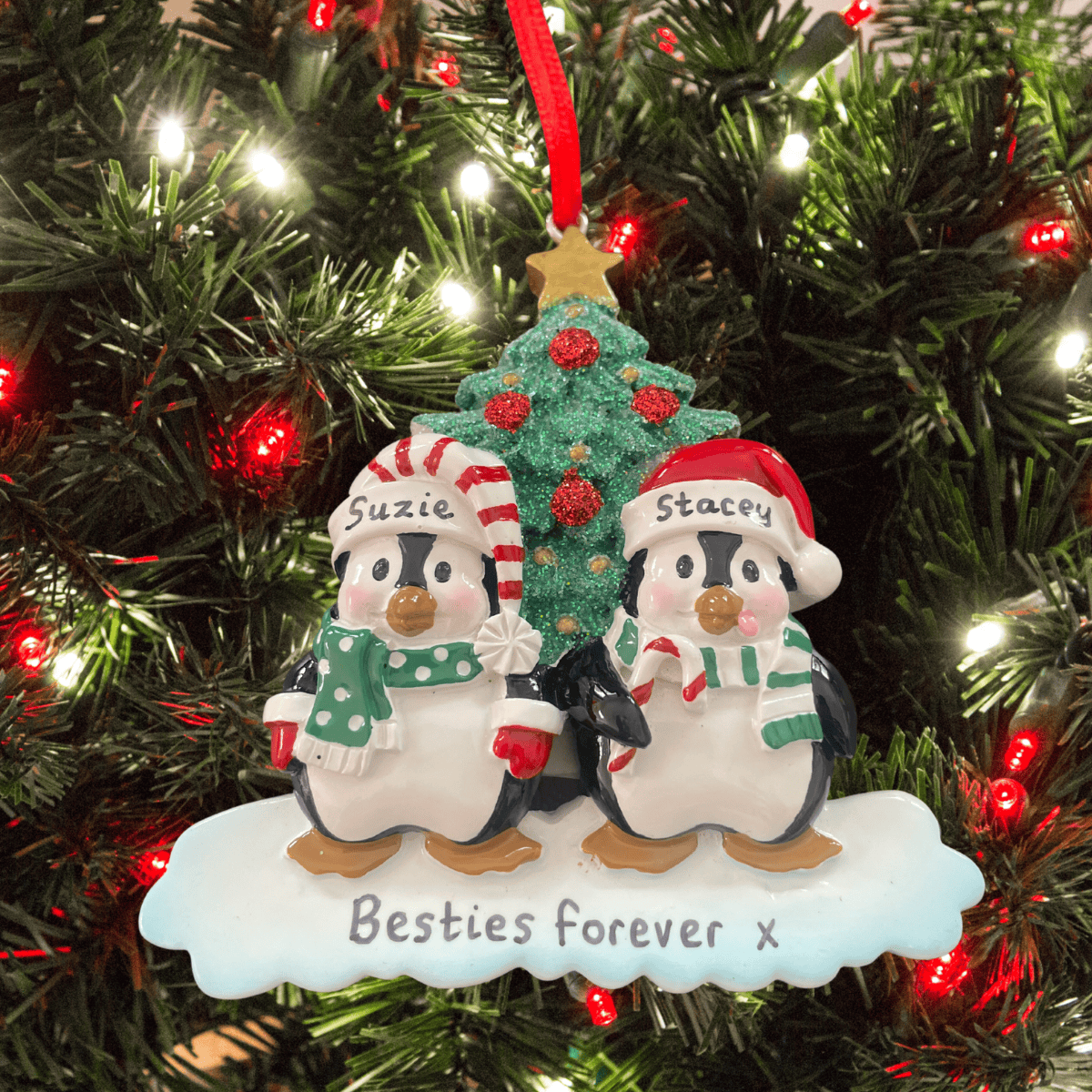 Two penguin ornaments with a Christmas tree in the background